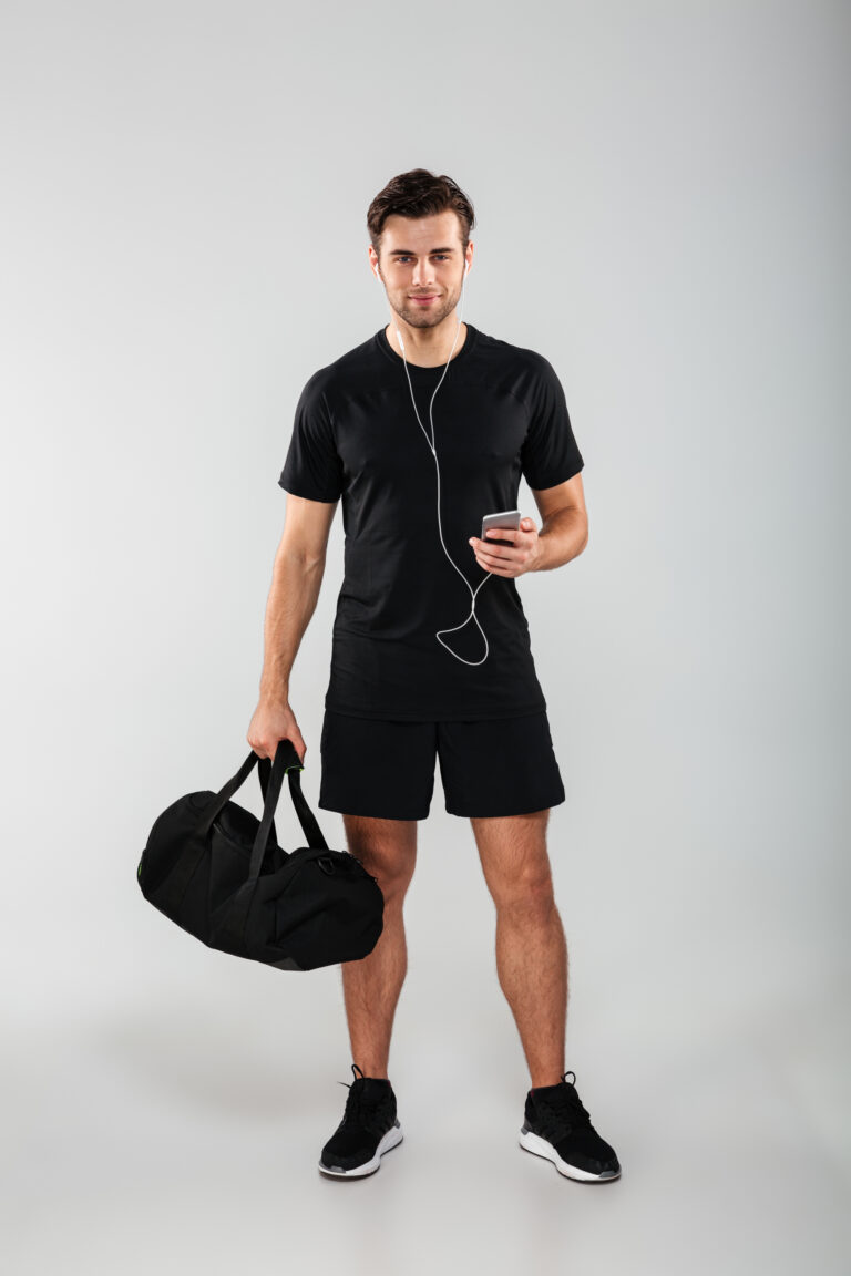 handsome cheerful young sports man using phone listening music