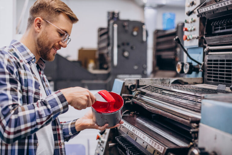 man working in printing house with paper and paints